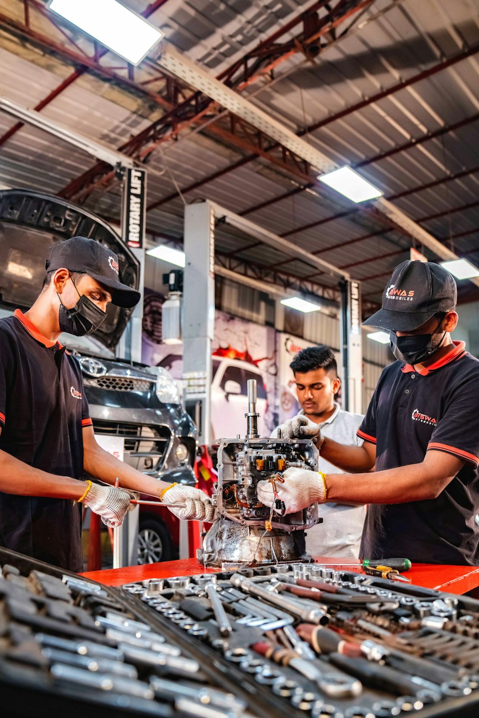 Mechanics working on a car engine at a workbench.