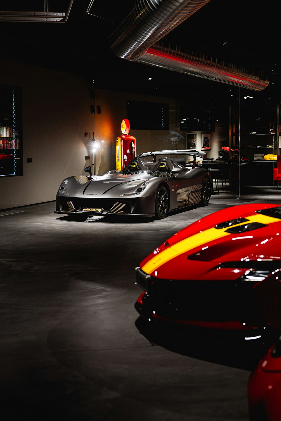 Grey sports car parked inside a modern industrial showroom.